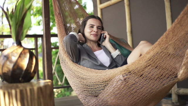 Young businesswoman talking on cellphone on hammock, super slow motion 240fps

