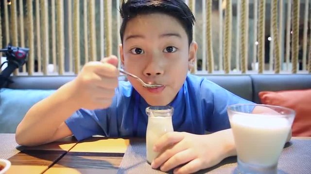 Happy asian boy eating dessert with smile face