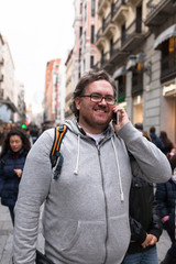 An urban young man talking through his smartphone outdoors in a busy street