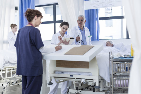 Doctor And Nurse At Very Sick Patient's Bed In Hospital