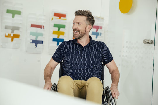 Smiling man in wheelchair in modern office