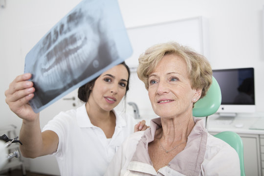 Dentist explaining x-ray image to senior woman in dentist's chair