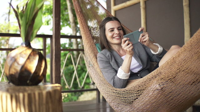 Happy businesswoman playing game on smartphone on hammock, super slow motion 240fps
