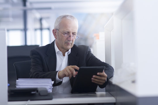 Businessman in open space office using digital tablet
