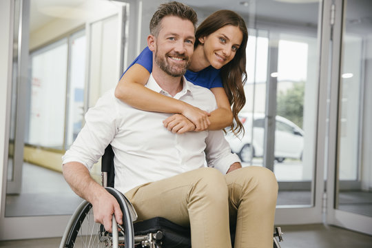 Man in wheelchair with his girlfriend, embracing happily