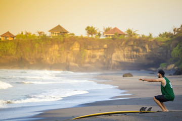 Indonesia, Bali, surfer on the beach doing a knee bend