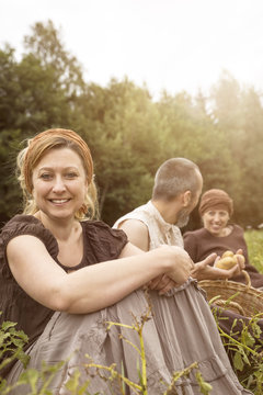 Smiling woman and two other people sitting on potato field