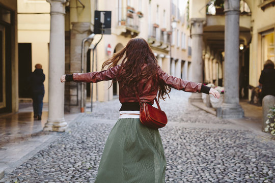 Italy, Padua, woman walking with outstretched arms in an alley