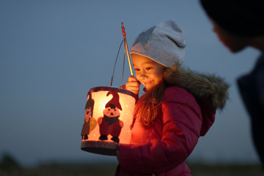 Smiling little girl with self-made paper lantern in the evening