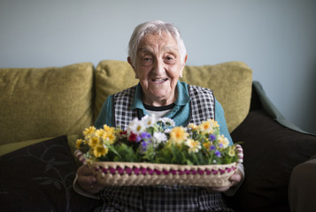 Portrait of senior woman showing a basket decorated with artificial flowers