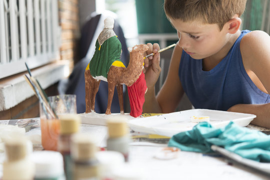 Boy painting nativity figurines