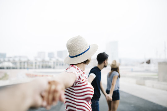 Spain, Barcelona, four friends holding hands