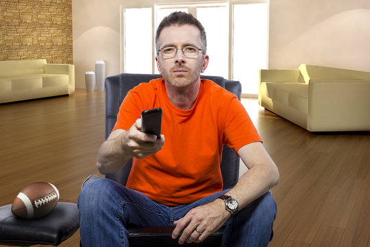 Front view of male sitting in a living room watching football on tv