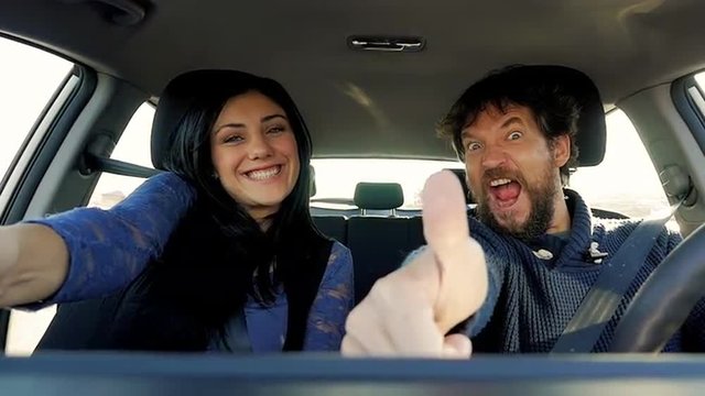 Man and woman making ok sign while driving car