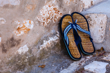 Beach flip-flops on the old wall background