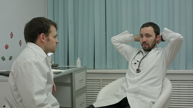 Two doctors relaxing at modern hospital indoors, speaking about life and work