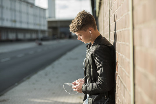 Young man wearing earbuds looking at cell phone