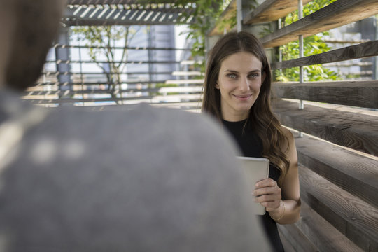 Smiling young woman with digital tablet in pergola