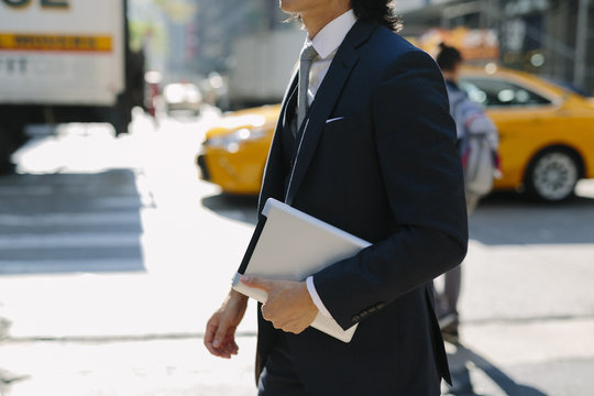 USA, New York City, businessman walking with digital tablet in Manhattan