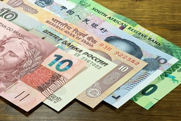 Banknoten der BRICS Staaten auf Holzhintergrund