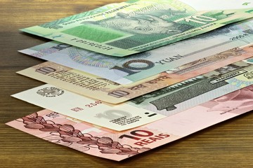 Banknoten der BRICS Staaten auf Holzhintergrund