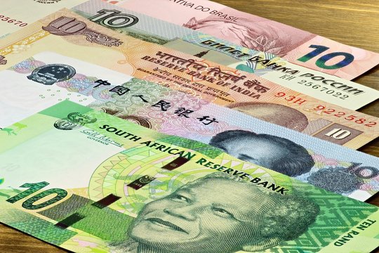 Banknoten der BRICS Staaten auf Holzhintergrund
