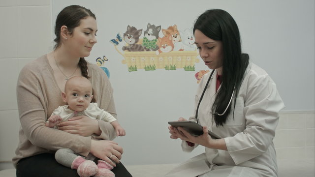 friendly pediatrician doctor explain something to mother with newborn baby