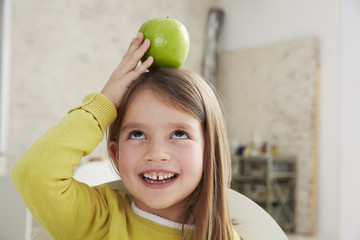 Germany, Munich, Girl sitting at table with green apple