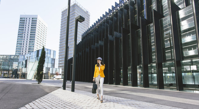 Spain, Catalunya, Barcelona, young modern woman with yellow jacket on the move