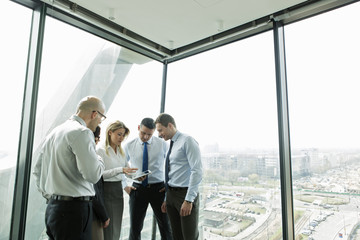 Businesspeople in office with woman using digital tablet