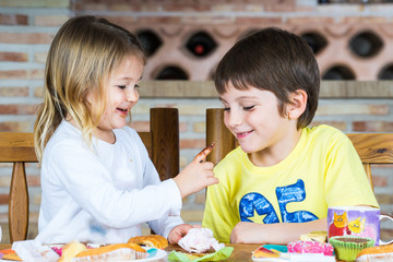 Fototapeta premium Pareja de niños jugando en la mesa con restos de comida
