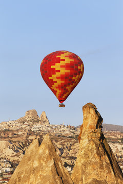 Turkey, Cappadocia, hot air balloon hoovering in front of the village Uchisar at Goereme National Park