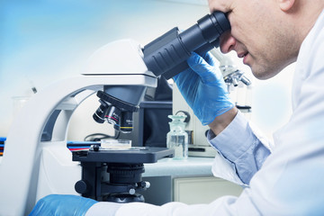 Scientist looking through microscope in laboratory