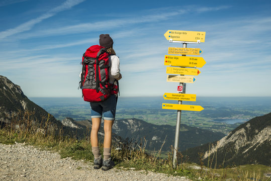 Naklejki Austria, Tyrol, Tannheimer Tal, young woman on hiking trip at signpost