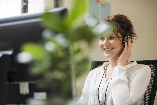 Smiling young woman in office wearing headset