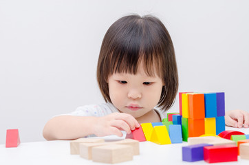 little Asian girl playing colorful wood blocks