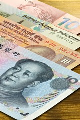 Banknoten der BRIC Staaten auf Holzhintergrund