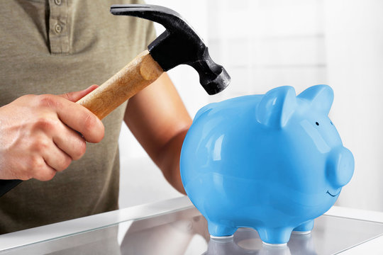 Man with a hammer going to break the piggy bank, close up