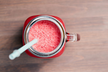 Watermelon smoothie in a mason jar on wooden background