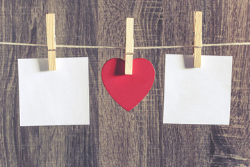 Love concept. Red heart and blank white cards hanging on a clothesline against a wooden background