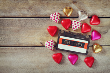 top view image of colorful heart shape chocolates and audio cassette on wooden table. valentine's day celebration concept