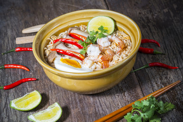 Thai food style noodle, tom yum kung on wood background