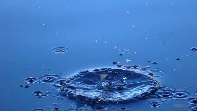 Slow motion close up scene with big boulder falls into the calm blue water. Impressive moving background with meditative effect. Relaxing view of the calm water. Full HD footage 1920x1080.
