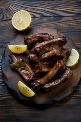Baked pork ribs served with lemon on a wooden chopping board