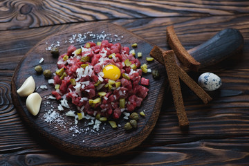 Rustic wooden chopping board with beef tartar, studio shot