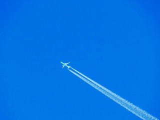 Airplane with chemtrails on blue sky