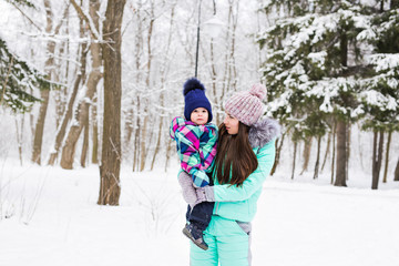 happy family mother and child baby daughter on a winter walk in the woods