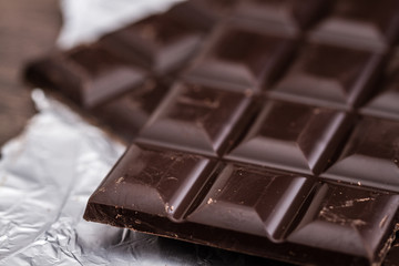 Dark Chocolate Bars on Foil and Wooden Table