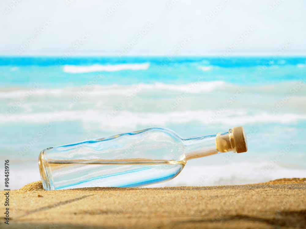 Wall mural bottle with water on the sea sand