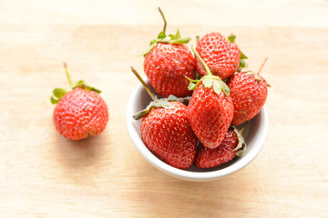 Strawberry in a cup on a wooden floor